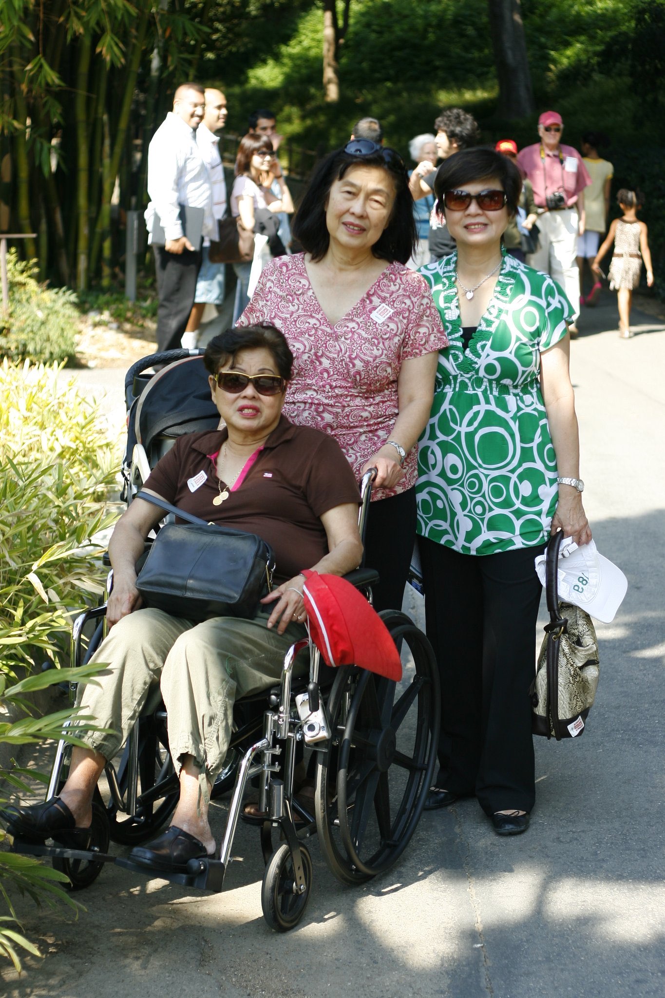 Three women smiling together on a garden pathway
