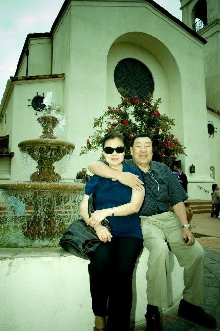Mom and Dad sitting together by a fountain outside St. Mary's church